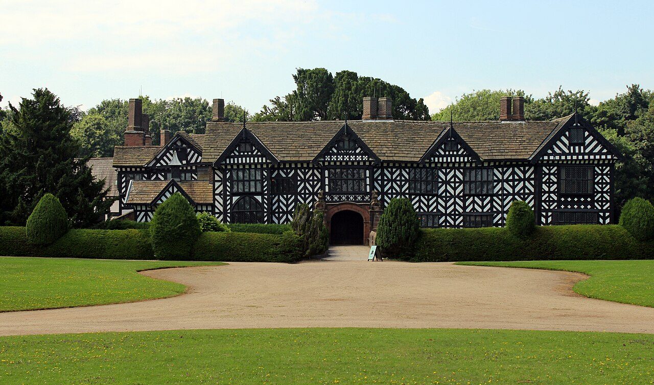 The black and white timbered front of Speke Hall seen across the lawn