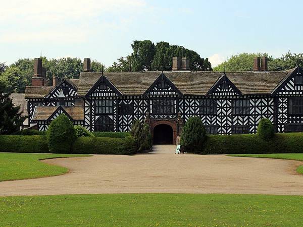The black and white timbered front of Speke Hall seen across the lawn